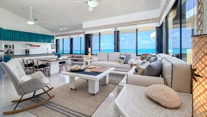 Uma sala de estar espaçosa com sofá, cadeiras, mesa de centro e vista para o oceano.