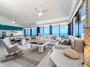 A spacious living area with a sofa, chairs, a coffee table, and a view of the ocean. - Penthouse Paradise | Wraparound Ocean Views (Isla Mujeres)