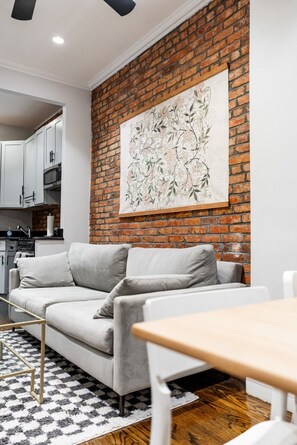 Ein modernes Wohnzimmer mit einer Couch, einem Couchtisch und einer Küchenzeile mit Schränken und Geräten.