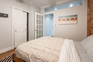 Un dormitorio con cama, una puerta, un armario y un cuadro en la pared.