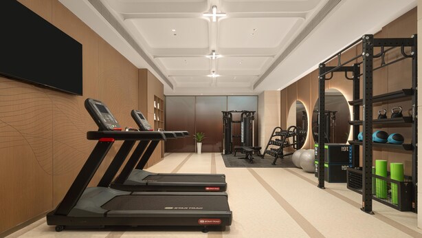 Et fitnesscenter med løbebånd, styrkemaskiner og en væg af spejle.