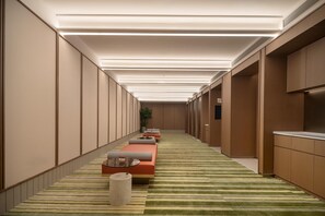 A hallway with a checkered bench, a small table, and a potted plant. - Hilton Garden Inn Shaoxing Keqiao China Textile City Station (Shaoxing)