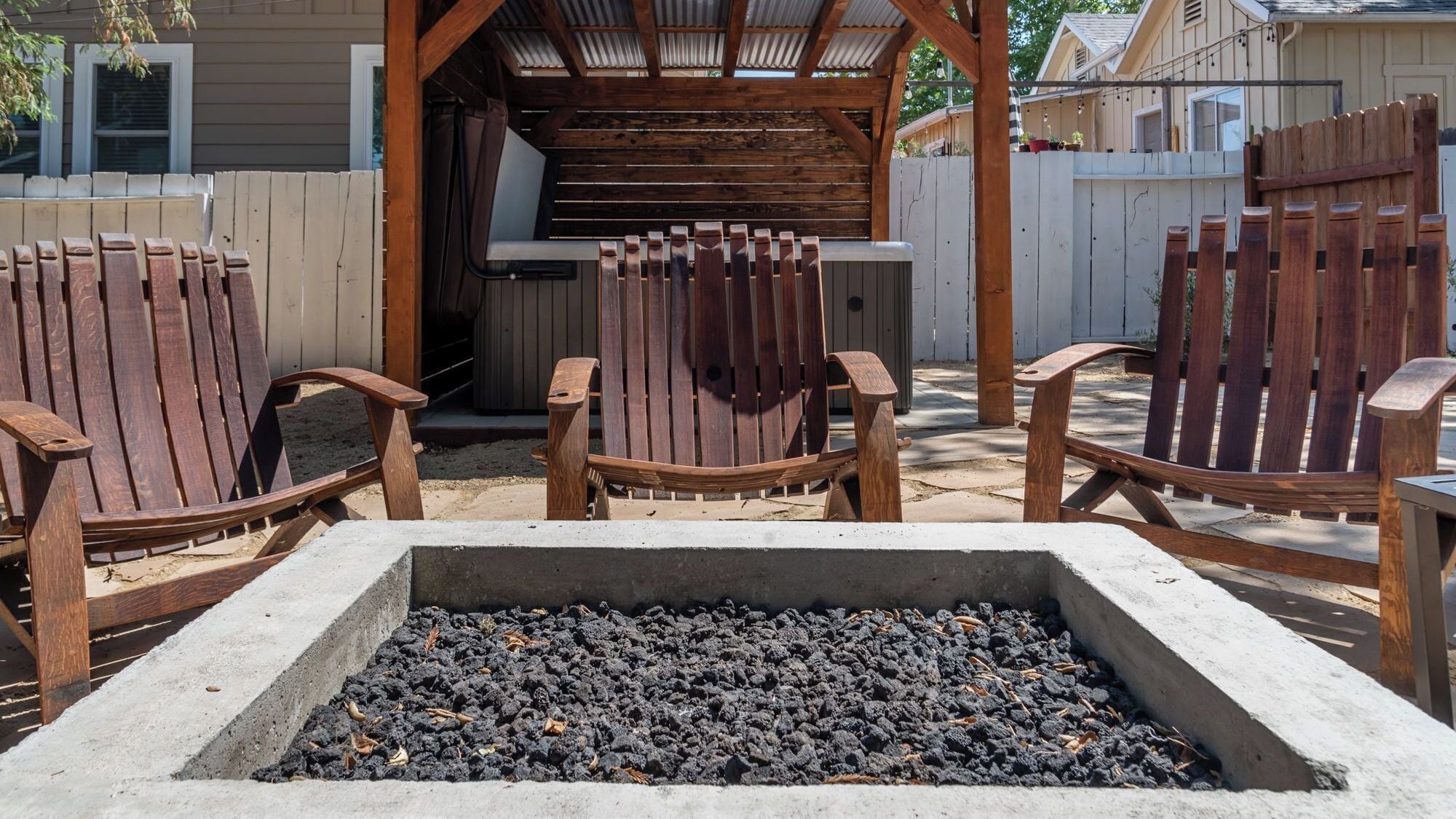 Eine Terrassenfläche mit Feuerstelle, Holzstühlen und Grill.
