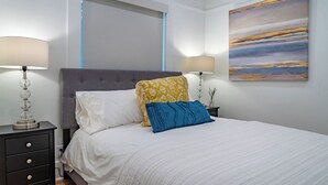 Un dormitorio con una cama, dos mesitas de noche y un cuadro en la pared.
