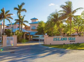 A resort entrance with a sign reading 'ISLAND SEAS RESORT,' palm trees, and a building with a blue roof. - Cozy 1-bedroom apartment with AC in welcoming Freeport (Freeport)