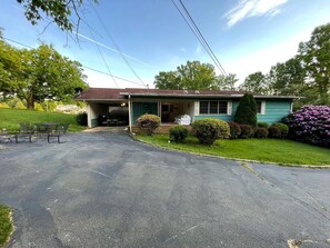Ein eingeschossiges Haus mit Veranda, Garage und gepflegtem Rasen.