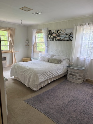 A bedroom with a bed, a nightstand, a lamp, a window with curtains, and a wall-mounted shelf. - Tranquil 3-bedroom house with AC in charming Spruce Pine (Spruce Pine)