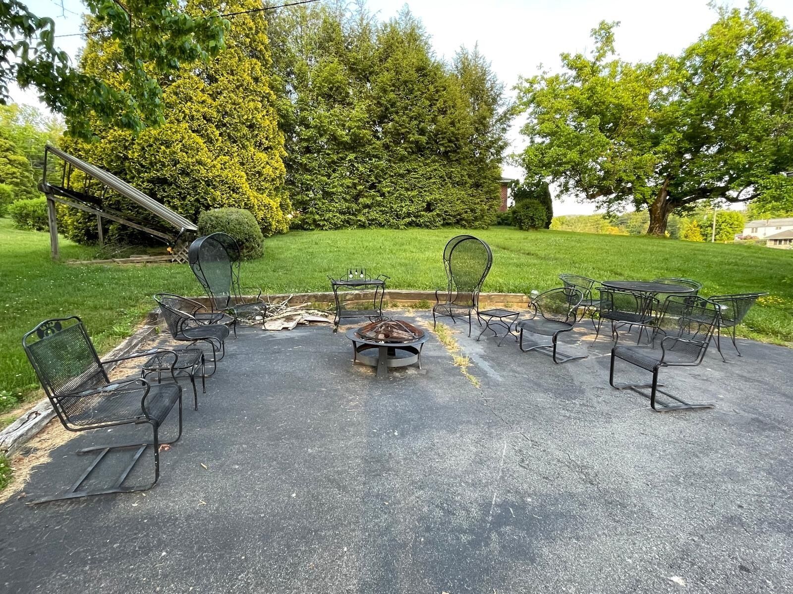 An outdoor patio with metal chairs and a fire pit.