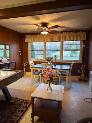 Un comedor con mesa de madera, sillas, un jarrón de flores y un ventilador de techo.