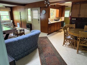 A living room with a pool table, a blue sofa, and a dining area with wicker chairs. - Tranquil 3-bedroom house with AC in charming Spruce Pine (Spruce Pine)