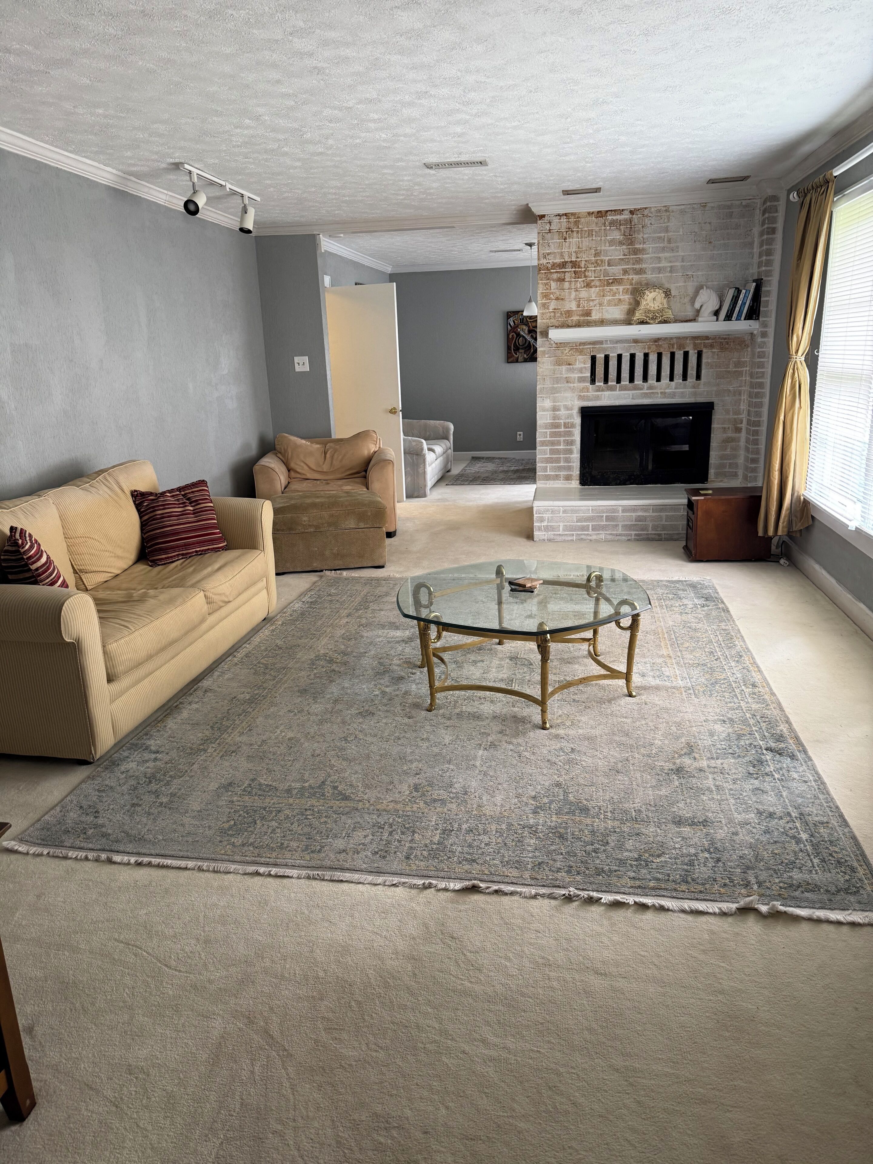 A living room with a beige sofa, a glass coffee table, and a fireplace.