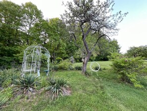 A garden with a metal birdcage, a tree, and various plants. - Tranquil 3-bedroom house with AC in charming Spruce Pine (Spruce Pine)