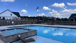 A swimming pool with a hot tub, lounge chairs, and a flag. - Refuge at Augusta 12 Min to LU  Quiet Community with private Screened Porch (Rustburg)