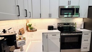 A modern kitchen with white cabinets, a microwave, an oven, and a coffee machine. - Refuge at Augusta 12 Min to LU  Quiet Community with private Screened Porch (Rustburg)