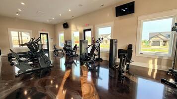 Ein Fitnessstudio mit Cardiogeräten, Gewichtstrainingbereichen und einem großen Fenster mit Blick nach draußen.