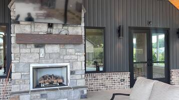 A modern outdoor living space with a stone fireplace, a round table, and a sofa.