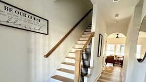 A staircase with wooden steps and a handrail, leading to a living area with a sofa and a coffee table. - Refuge at Augusta 12 Min to LU  Quiet Community with private Screened Porch (Rustburg)