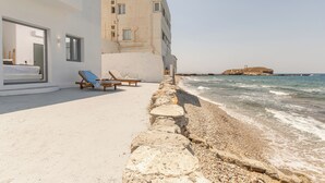 Een kusthotel met een balkon, lounge stoelen en uitzicht op zee.