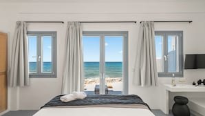 Een slaapkamer met een bed, een bureau en uitzicht op het strand.