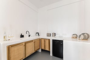 Una cocina moderna con encimeras blancas, gabinetes de madera, lavavajillas y diversos electrodomésticos.