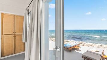 A room with a view of the sea, a wooden wardrobe, and a beachside lounge area.