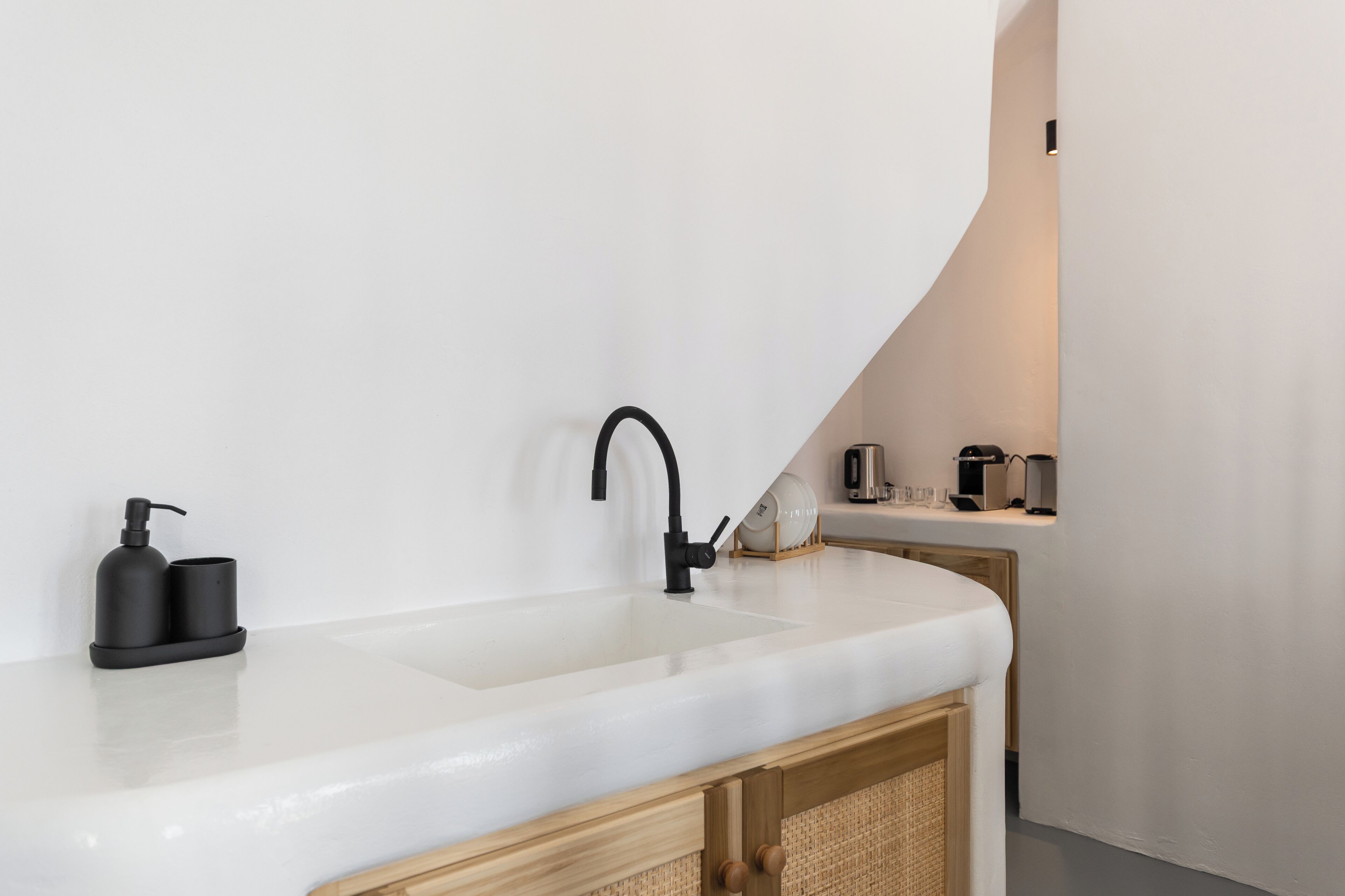 A modern kitchen with a white countertop, a black faucet, and a coffee machine.