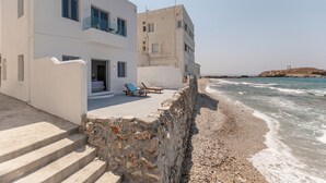 Een gebouw aan de kust met een balkon, een trap naar de ingang en uitzicht op zee.
