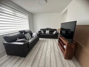 Ein Wohnzimmer mit einem Ecksofa, einem Flachbildfernseher und einer Holzunterhaltungsecke.