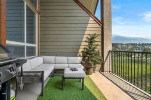 Ein Balkon mit einer Eckcouch, einem kleinen Tisch und einem Grill.