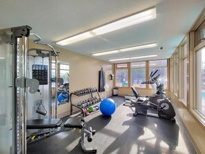 Ein Fitnessraum mit Trainingsgeräten, einem blauen Gymnastikball und einem Ergometer.