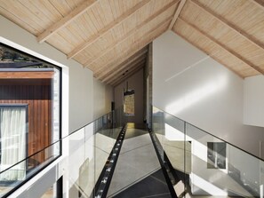 Ein modernes Interieur mit Glastrennwand, Holzboden und Blick durch ein Fenster.