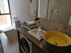 A bathroom with a washing machine, a yellow sink, a towel, and a mirror. - Appartamento del Bosco, Ref: VDA_LT_AOSTA_0852 (Aosta)