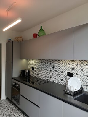 A modern kitchen with grey cabinets, a black countertop, and a patterned backsplash. - Appartamento del Bosco, Ref: VDA_LT_AOSTA_0852 (Aosta)
