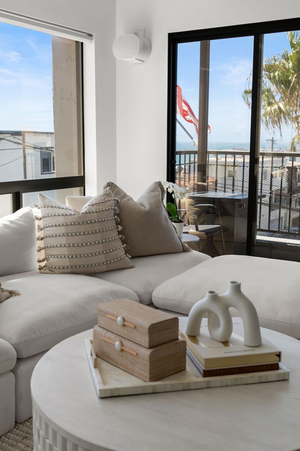 A modern living room with a large window, a sofa, and a coffee table with decorative items.
