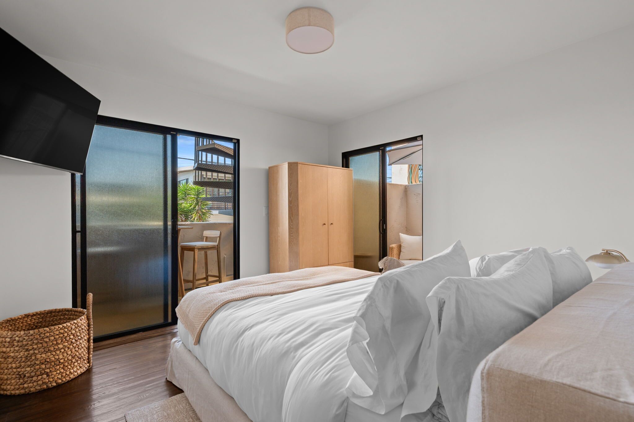 A modern bedroom with a bed, a wardrobe, and a balcony with a view.