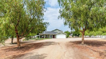 Una casa a un piano con garage, immersa nel verde e con vialetto in ghiaia.