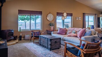 A cozy living room with a sofa, chairs, a wooden chest, and a large window with a view.
