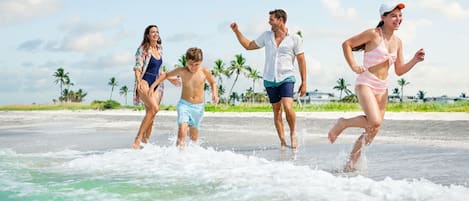 A beach scene with people running on the sand.