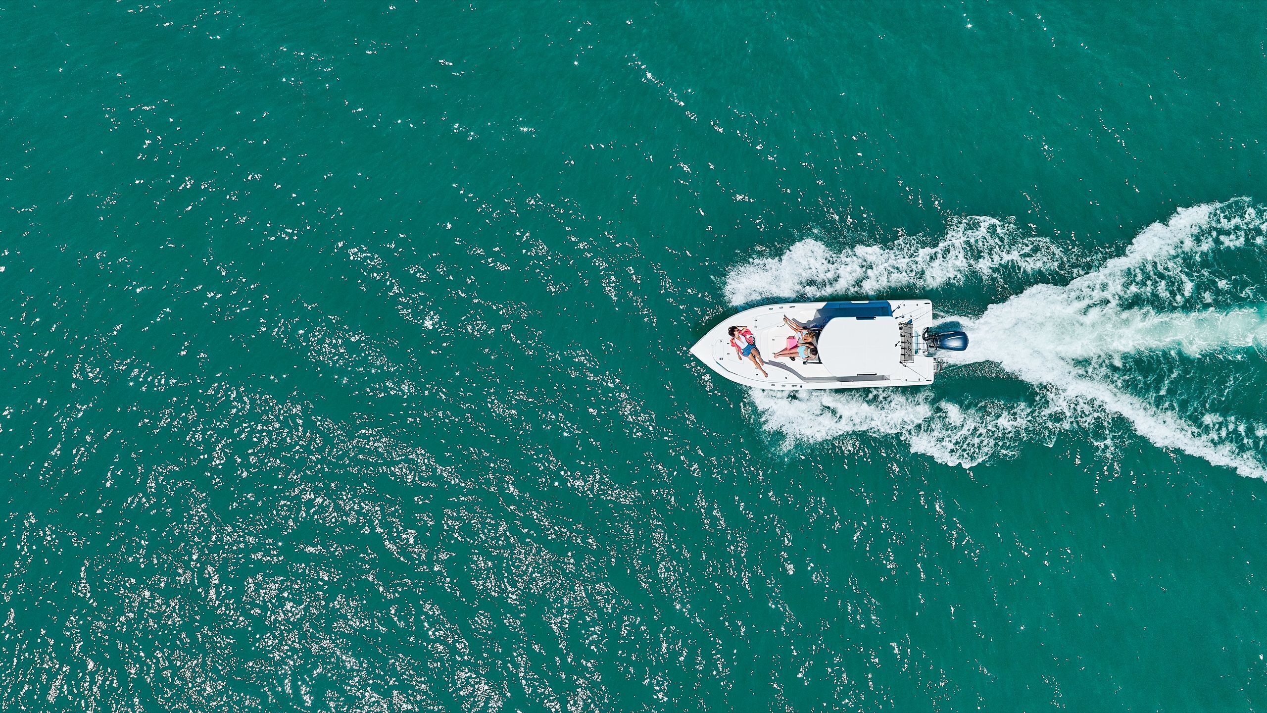 A boat with passengers on a turquoise sea.