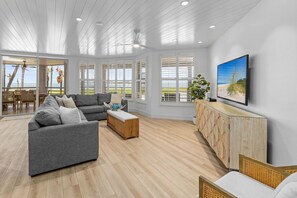 A spacious living room with a grey sofa, wooden coffee table, and a TV on a wooden cabinet. - South Seas Resort | 3BR Land's End Villa (Captiva)
