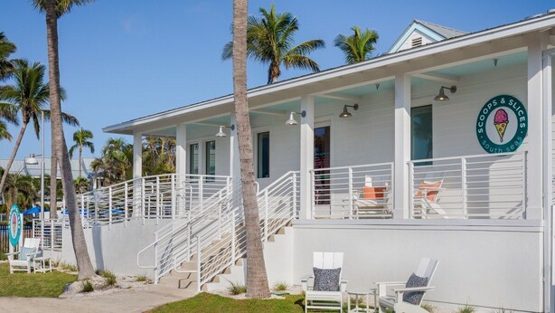 A beachfront building with a covered patio, palm trees, and outdoor seating. - South Seas Resort | 1BR Villa Near Captiva Landing (Captiva)