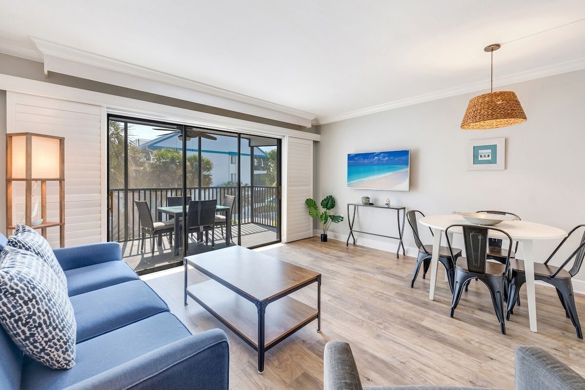 Uma sala de estar moderna com sofá, mesa de centro e área de jantar.