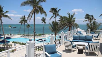 A poolside area with lounge chairs and a view of the ocean.