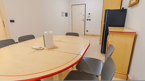 Ein Konferenzraum mit rundem Tisch, Stühlen, einer Whiteboard-Tafel und einem Schrank.