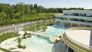 Un hotel con una grande piscina, una fontana e un giardino curato.