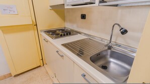 Una cucina con un lavello in acciaio inossidabile, un fornello a quattro fuochi e un rubinetto.