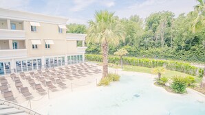 Ein Hotel mit Poolbereich, Liegestühlen und einer Palme.
