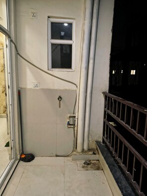 Ein Zimmer mit Tür, Fenster, einem Mop und einer Geländer.