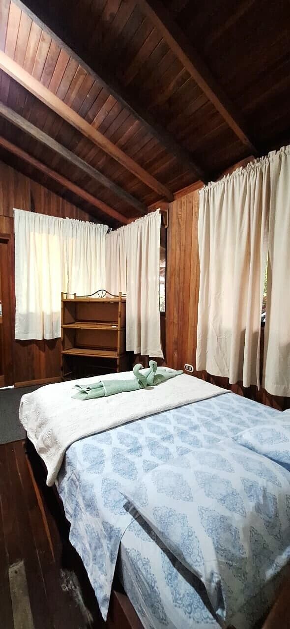 Habitació de fusta amb un llit, una prateleira i cortines.
