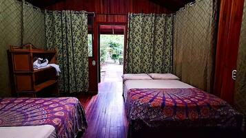 Una habitación con dos camas, un banco de madera y una puerta que da al exterior.